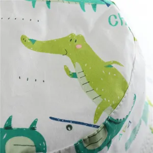 Kids pure cotton sun hat detail showing cute green crocodile cartoon print and soft fabric texture.