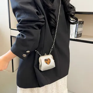 Chic silver kiss-lock crossbody bag with chic heart leopard pattern and stylish chain.