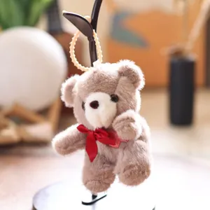 Cute brown plush teddy bear pendant detail, soft fur and red ribbon bow, bag charm keyring.