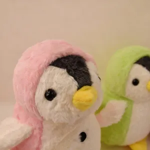 Cute plush penguin doll with soft pink and green hooded design, detailed close-up shot.