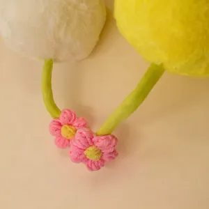 Cute plush toy detail featuring fluffy white and yellow balls with green stems and pink flowers.