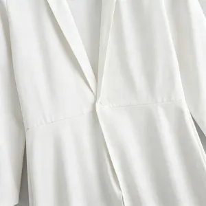 Close-up detail of white men's long blazer, featuring lapel collar, single button and waist design.