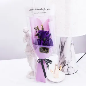 Purple rose soap flower bouquet in transparent gift bag with ribbon for Valentine's Day event.