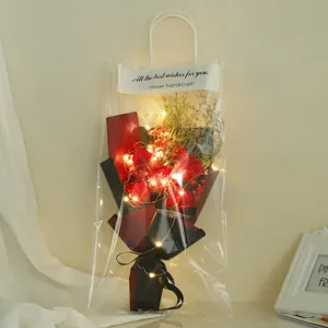 Transparent gift bag rose bouquet detail view with warm fairy lights and dried flowers.
