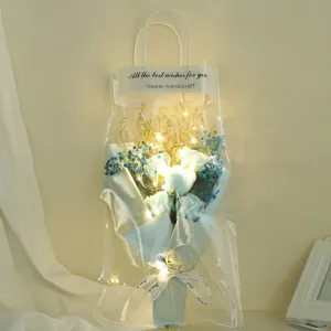 Detailed view of lighted blue rose bouquet in transparent gift bag with fairy lights and ribbon.