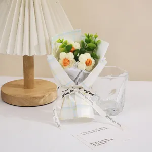 Detail view of handmade crochet mini flower bouquet wrapped in cute summer plaid paper with ribbon.