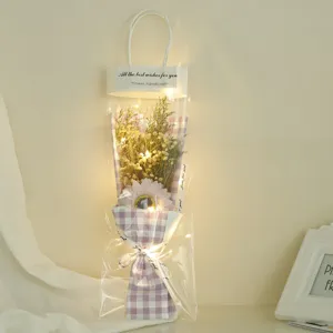 Gift wrapped dried flower bouquet with fairy lights in purple plaid bag for romantic occasions.
