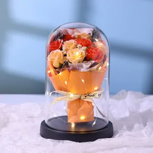 Close-up of glowing rose bouquet in glass dome with fairy lights for romantic home decor.