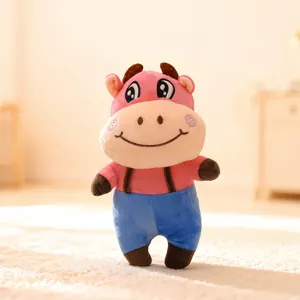 Detailed view of the cute pink plush cow toy wearing blue overalls, soft stuffed animal doll model.