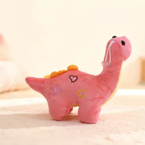 Cute pink dinosaur plush toy with heart embroidery and suction cup detail closeup.