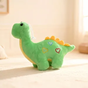 Close-up detail view of the green dinosaur plush toy showing soft fabric and cute heart embroidery.