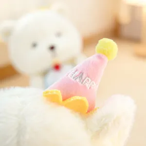 Close up detail of cute plush toy wearing a soft pink party hat with happy embroidery design.