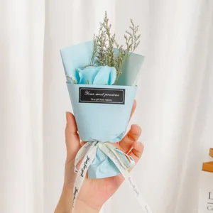 Detailed shot of mini blue soap rose bouquet with dried grass, elegant gift packaging design.