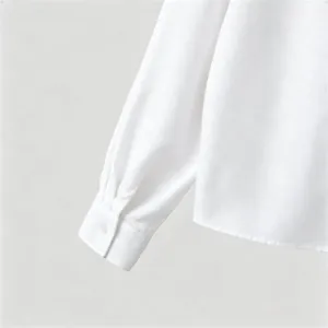 Detailed close-up view of white textured men's long sleeve shirt cuff and fabric texture.