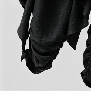 Detailed shot of black men's draped layered casual pants with textured fabric and twisted design.