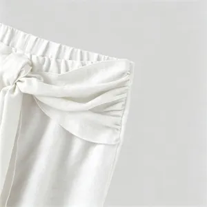 Men's casual trousers detail shot showing unique white waistband with knot and layered wrap design.