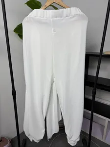 Men's white casual harem pants detail view, featuring layered draped panels and elastic waistband.