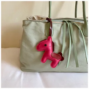 Detailopname van een stijlvolle lederen paarden-tassenhanger hangend aan een chique tas.