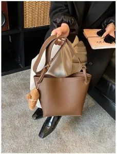 Détail du sac-seau élégant en cuir marron avec texture grainée et joli pendentif mignon.