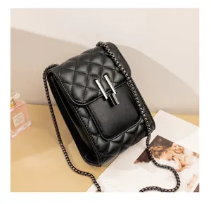 Detailed view of black quilted mini phone bag, metallic chain strap and chic lock closure.