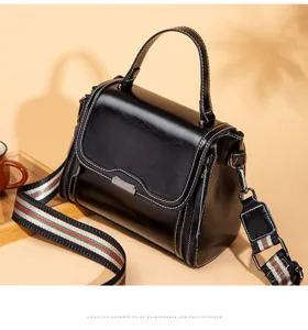 Black retro handbag detail, top handle bag with striped shoulder strap and metal clasp design.