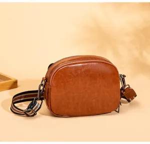 Close-up detail of retro brown crossbody shoulder bag showing texture and hardware.