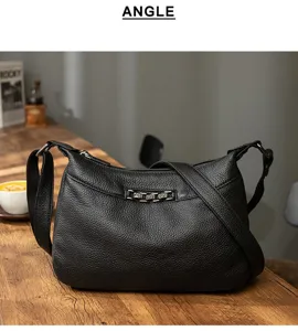 Detailed shot of black pebbled leather shoulder bag with chic metal chain accent on wooden table.