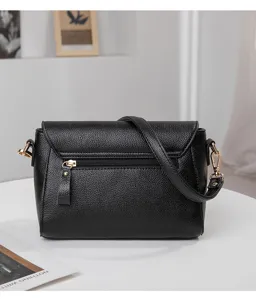 Détail du sac bandoulière noir en cuir grainé avec fermeture à rabat et détails dorés.