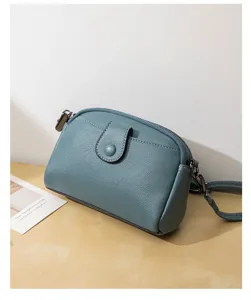 Detail view of the blue grey leather crossbody bag showing front pocket and fine texture.