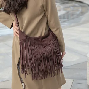 Sac bandoulière rétro en daim marron avec franges, sac hobo tendance porté par mannequin.