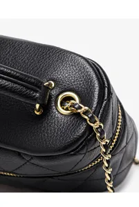 Close-up detail of black quilted leather crossbody bag with luxury gold chain strap and hardware.