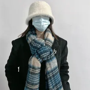 Detailaufnahme des flauschigen blauen Karo-Winterschals mit weißem Plüschhut und Blazer.