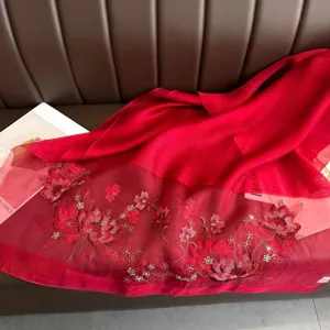 Detail view of red silk scarf featuring exquisite lotus embroidery for elegant wear.