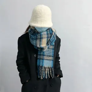 Detailaufnahme des kuscheligen blauen karierten Winterschals mit Fransen und Plüschhut.