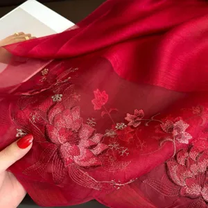 Close-up of exquisite red silk lotus embroidery scarf detail, elegant texture and pattern.