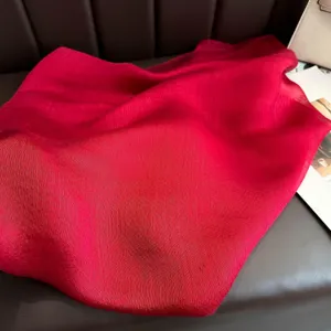 Red silk wool blend scarf detail shot, elegant soft shawl fabric texture display.