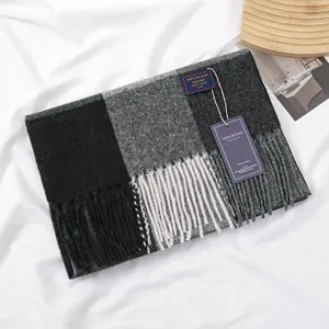 Detailed view of the cozy plaid cashmere-feel scarf with stylish fringes and brand tag design.