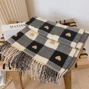 Detailed view of the cozy black and white plaid scarf featuring cute heart patterns and fringes.