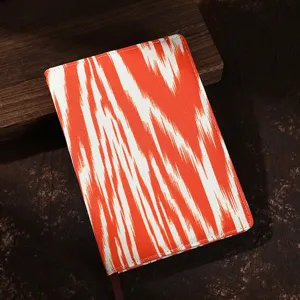 Detalle exquisito del cuaderno de tela étnica con un vibrante patrón Ikat naranja.