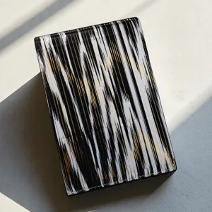 Cuaderno cultural de estilo étnico con llamativa cubierta de rayas verticales negro blanco y oro.