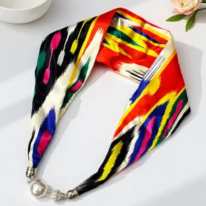 Close-up detail of the vibrant traditional Atlas silk scarf featuring an elegant magnetic pearl buckle.