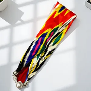 Detail view of the colorful ethnic silk scarf featuring a elegant pearl magnetic buckle.