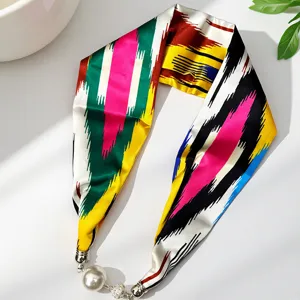 Silk scarf with pearl pendant, close-up view showing colorful abstract patterns and details.