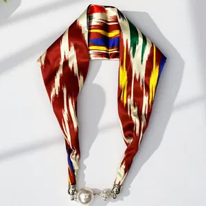 Exquisite detail of the silk scarf featuring traditional ethnic print and magnetic pearl clasp.