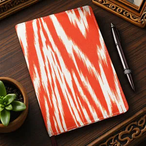 Exquisite Xinjiang ethnic style printed fabric notebook detail, vibrant orange and white ikat pattern design.