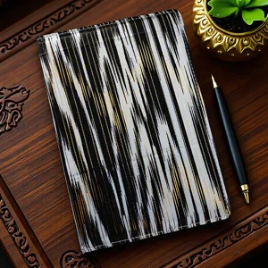 Detailed view of traditional ethnic style printed fabric notebook with pen and golden plant decor.