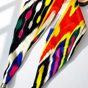 Silk scarf detail showing colorful ethnic pattern and magnetic pearl buckle closure.
