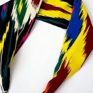 Close-up detail of colorful abstract printed silk scarf with magnetic buckle accessory.