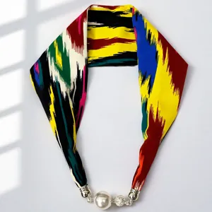 Detailed close-up of colorful ethnic silk scarf with pearl magnetic clasp and vivid ikat pattern.