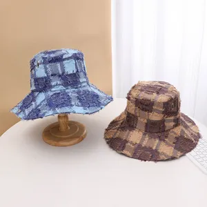 Detailed view of trendy fringe plaid bucket hats in blue and brown for outdoor sun protection.